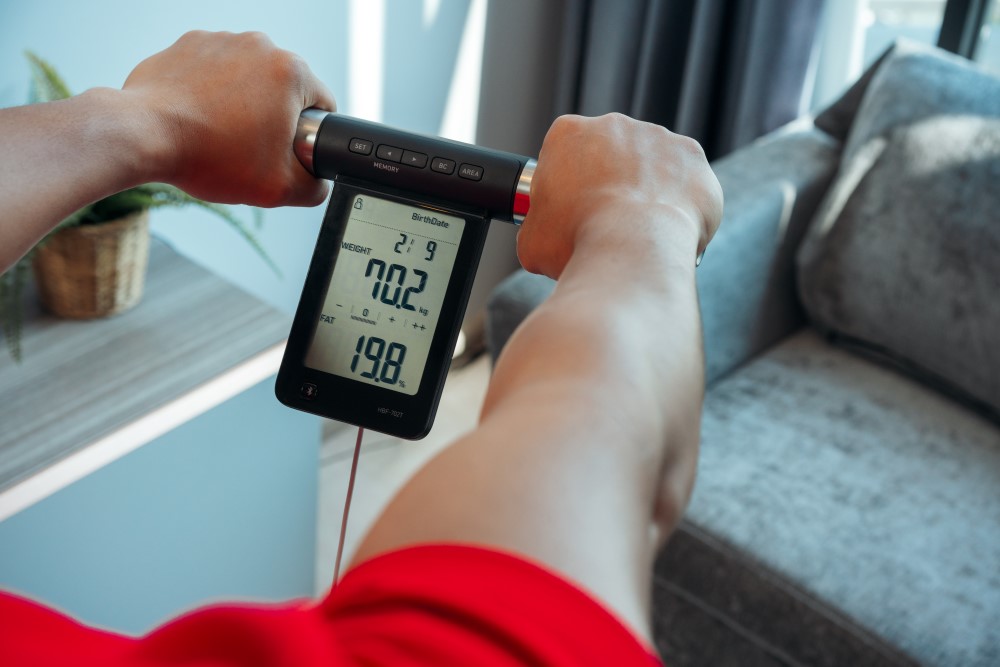 A person using OMRON body composition monitor to check his body composition.