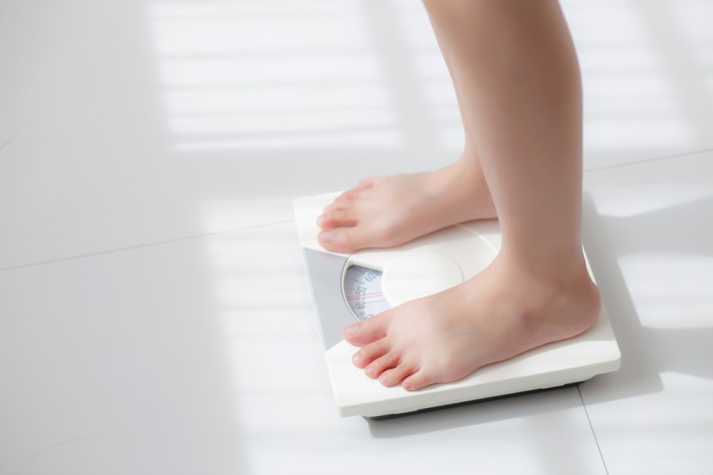 A person using the weighing scale to check his weight.