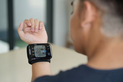 A man looking at his OMRON wrist blood pressure monitor.