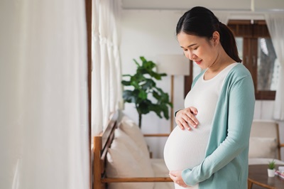A pregnant woman with her hand resting on her belly.
