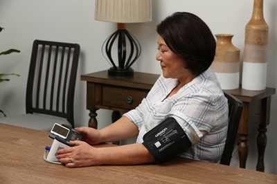 A woman using OMRON's blood pressure monitor.
