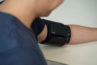 A person measuring his blood pressure using OMRON HEM-7600T.